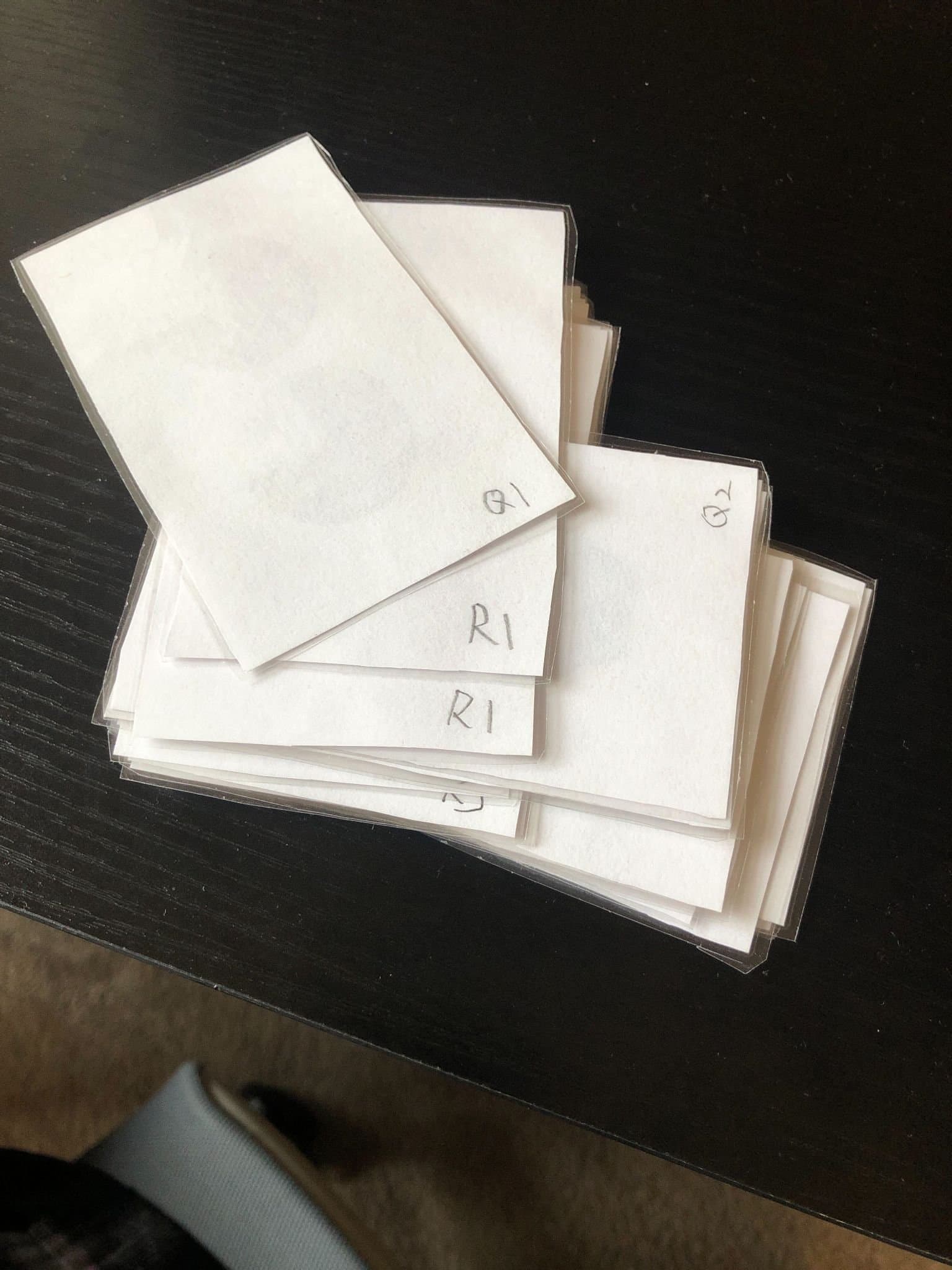 Stacks of laminated stimulus cards, hand-labeled Q1, R1, Q2, on a black table