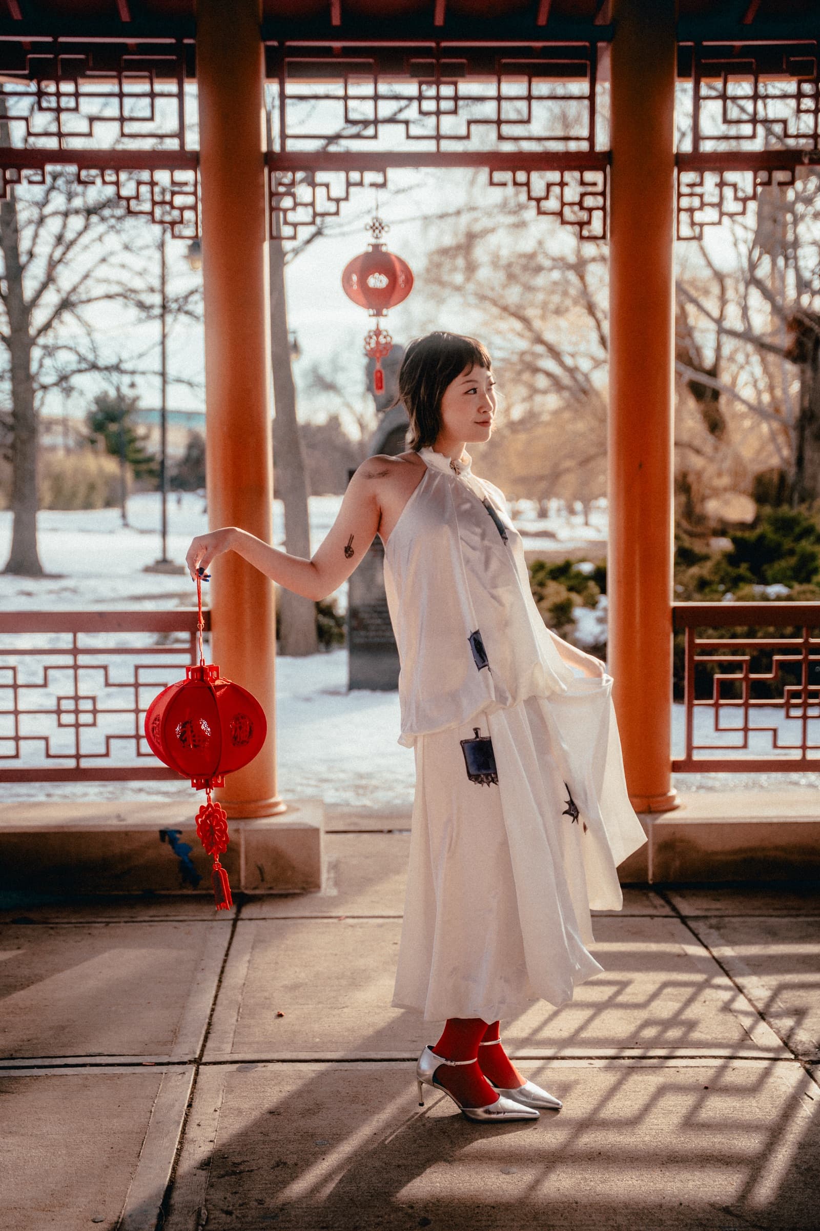 Turning in the pavilion, white dress catching the low sun, lantern held low